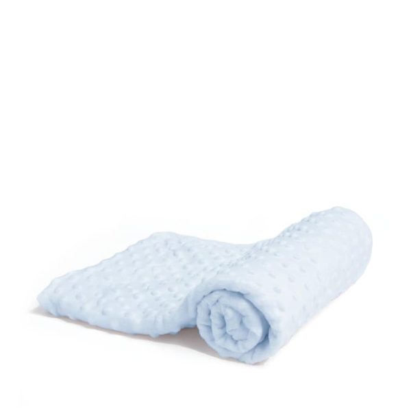 A white surface is depicted in this image, with a blue blanket placed on top. The blanket features a design of white dots, and the background is white as well.