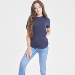 A girl is standing in the image, dressed in a blue shirt and blue jeans. The background is white, and the image appears to have been taken in a studio setting.