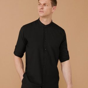 A man is standing in the image, dressed in a black shirt. The background is a light brown color.