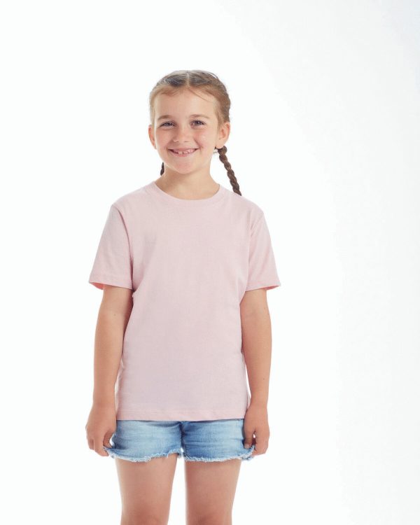 A girl is standing in the image, dressed in a pink shirt and blue shorts. The background is white, and the image appears to have been taken in a studio setting.
