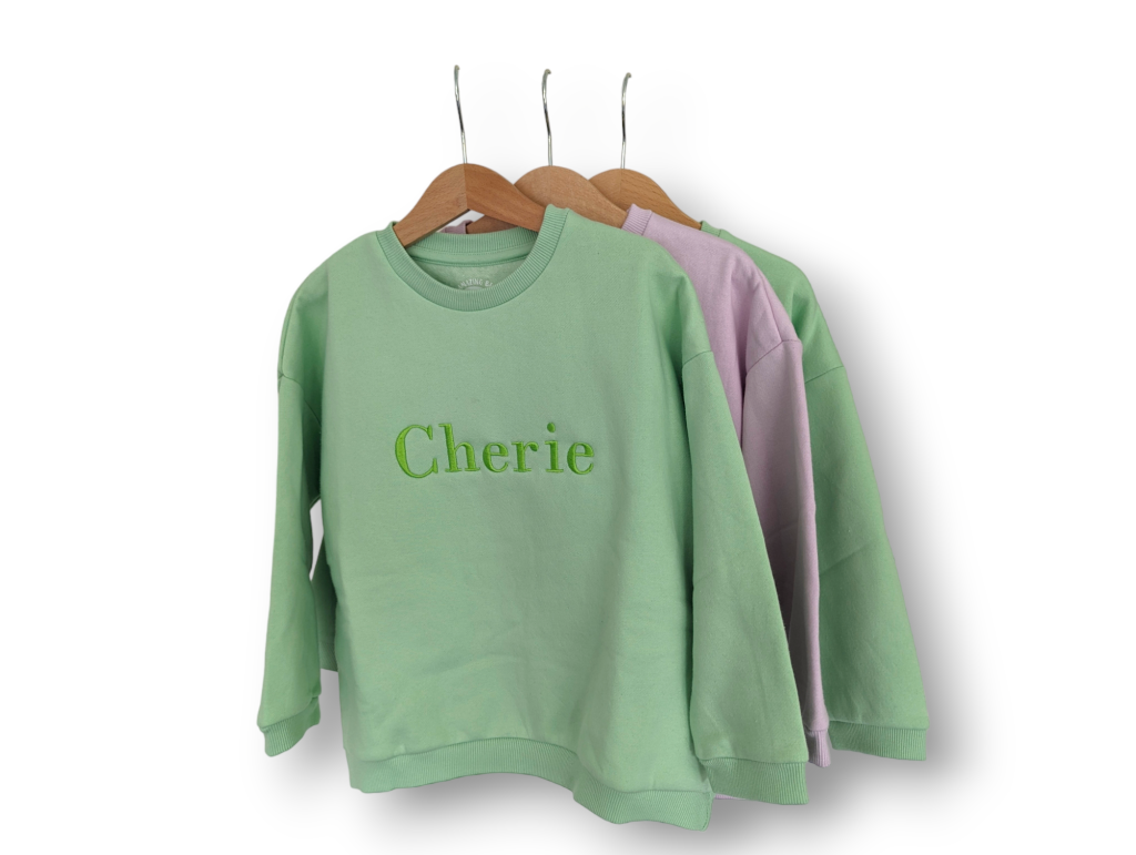 A collection of sweatshirts and trousers is displayed in this image, with the sweatshirt featuring the name "cherie. "