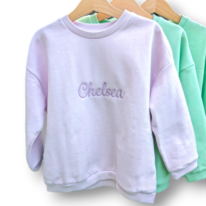 A collection of sweatshirts is displayed in this image, with the sweatshirt in the center featuring the name "Chelsea."