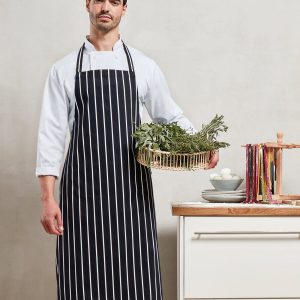 A man is standing in the image, holding a basket with plants and a bowl. The background features a wall, and a cupboard is situated to the right side of the image.