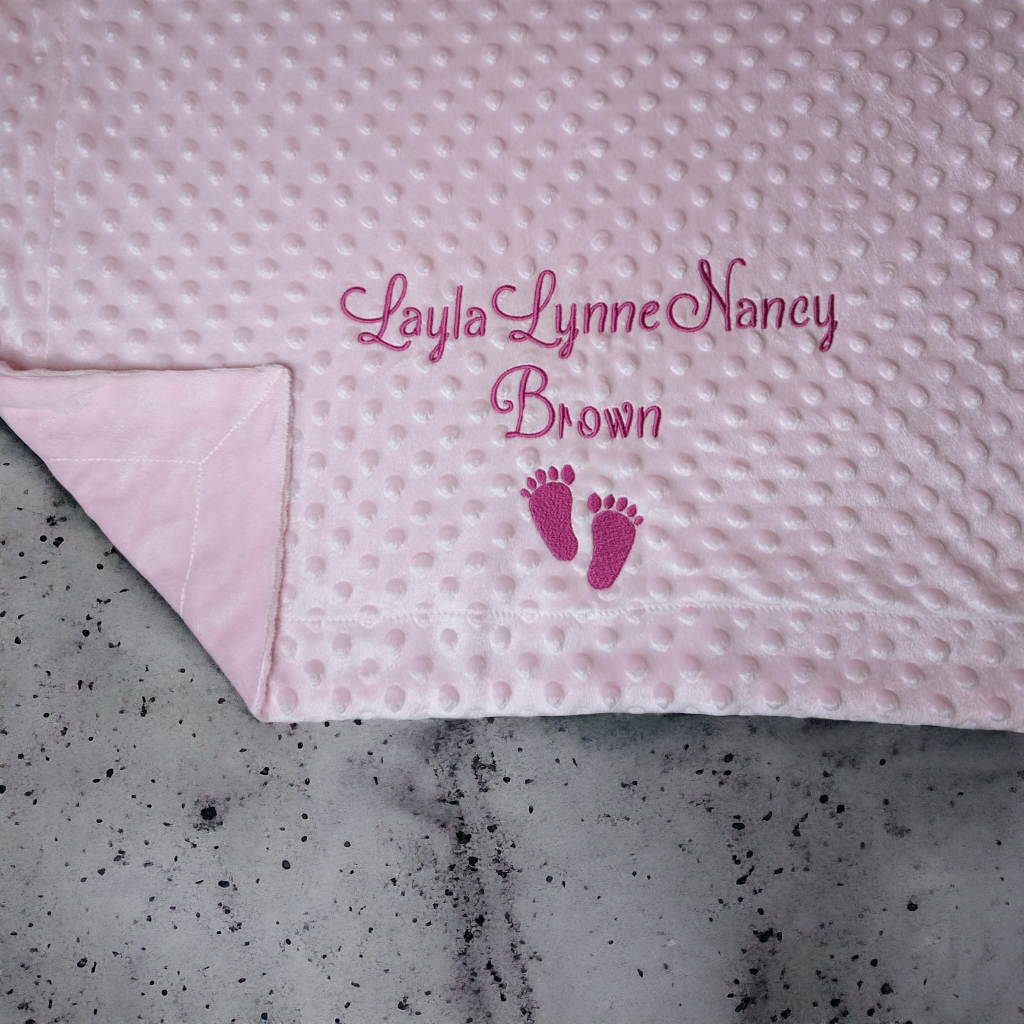 A pink blanket is depicted in this image, featuring a foot print and the name "lacey lynne nancy".