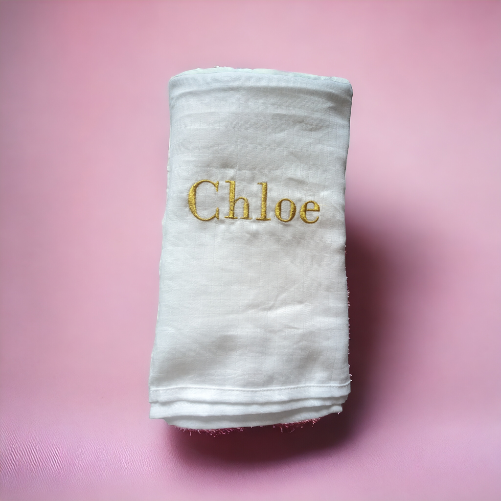 A white cloth is depicted in this image, featuring gold-colored text. The cloth is placed on a pink surface, which is also white in color.