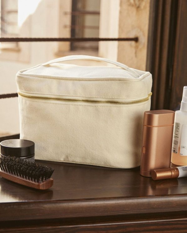 A white vanity case is the central focus of this image, with a brush and other items placed on top. The background features a wall, window, and a door.