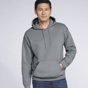 A man is standing in the image, dressed in a grey hooded sweatshirt. The background is white, and the image appears to have been taken in a dimly lit environment.