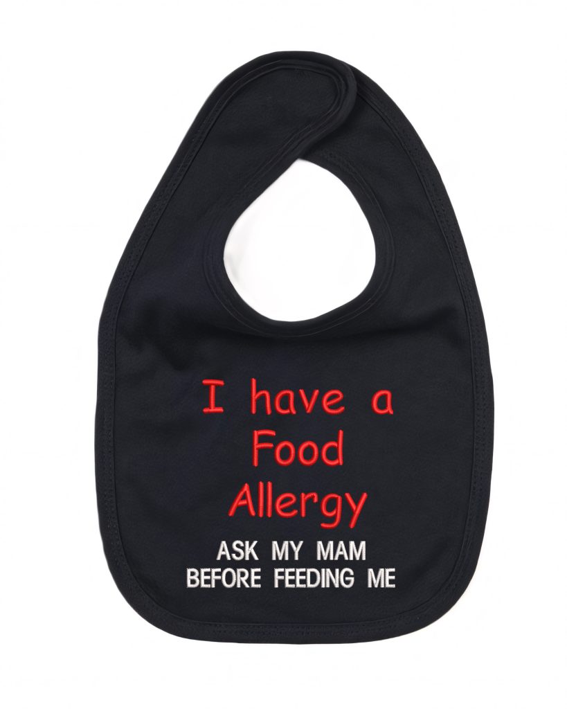 A black-colored bib is depicted in this image, featuring a red and black design. The word "food allergy" is written on the bib, along with some text.