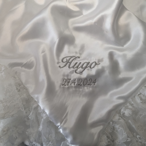 A white cloth is depicted in this image, featuring a logo and some text. The cloth is adorned with a few white flowers. The background is white.