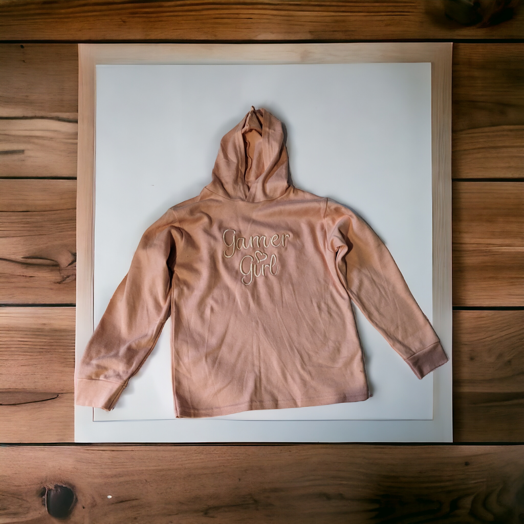 A hoodie is depicted in this image, featuring the name "jumper girl" written on it. The hoodie is placed on a wooden surface, which appears to be a wooden floor.