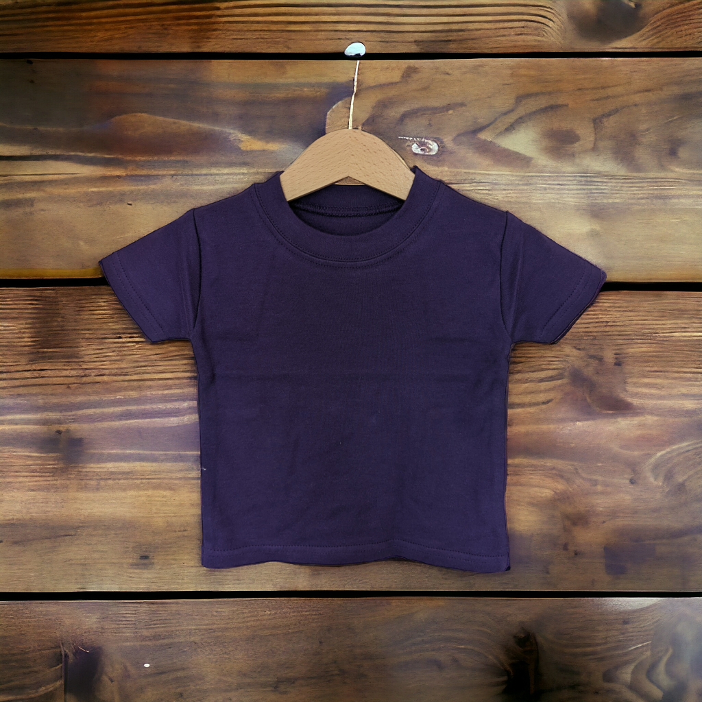 A child's t-shirt is displayed in the image, hanging on a wooden surface. The background is brown, and the image is taken from a close distance, making the details of the shirt and wooden surface visible.