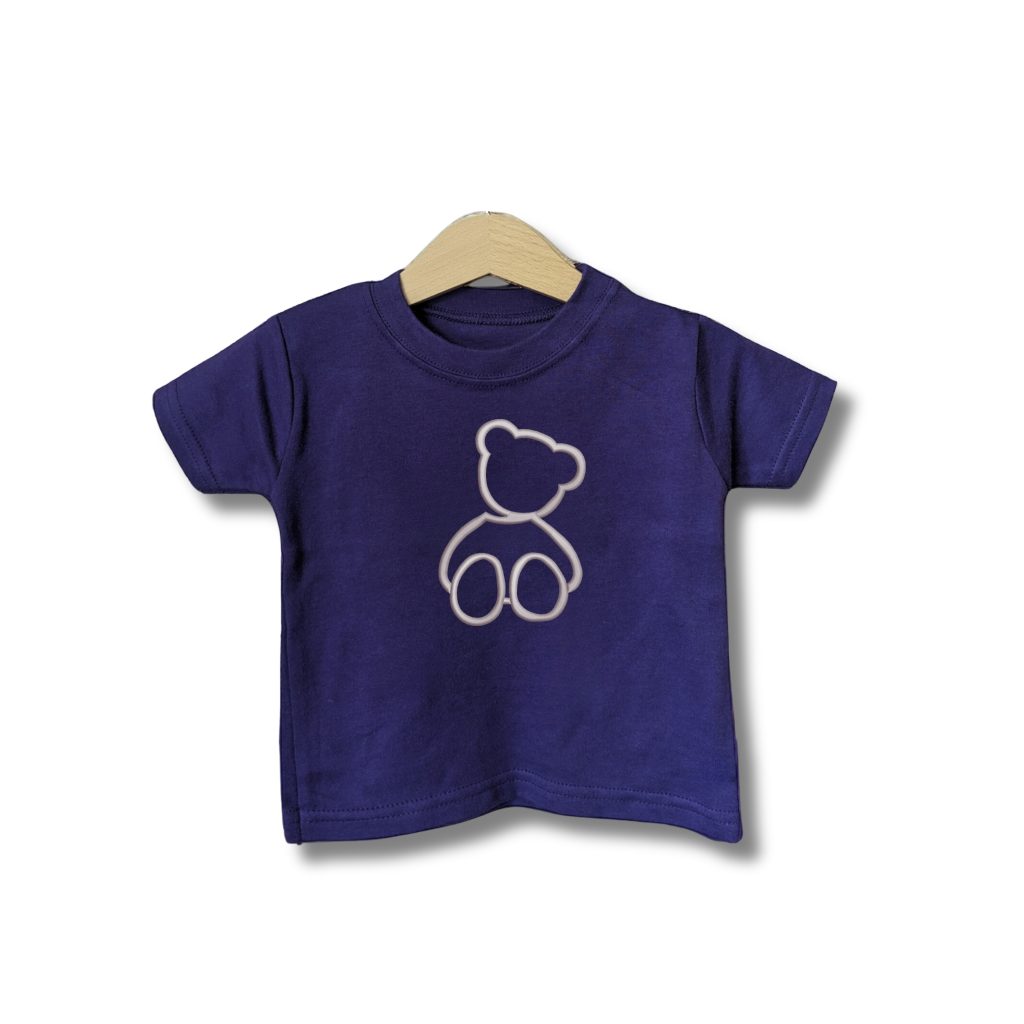 A baby t-shirt is displayed in the image, featuring a teddy bear outline in purple. The teddy bear is depicted in a white and cream color, with a light brown background.