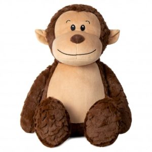 A stuffed monkey is the central focus of this image, with a white background. The monkey is dressed in a brown outfit and has a smiling face. The image is taken from a top-down perspective.