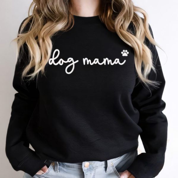 A woman wearing a black sweatshirt with the words "Dog Mama" embroidered along with an embroidered paw print