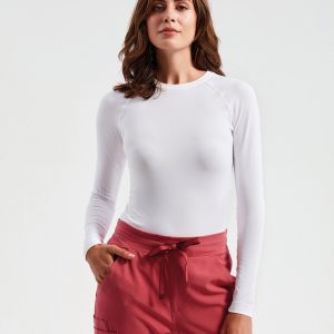 A woman is standing in the image, dressed in white. She is wearing a red dress and red pants. The background is white, and the image appears to have been taken in a dimly lit environment.