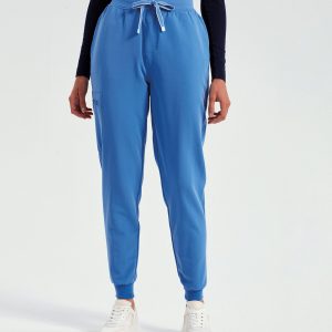 A woman is standing in the image, dressed in a blue top and white shoes. The background is white, and the image appears to have been taken in a dimly lit environment.