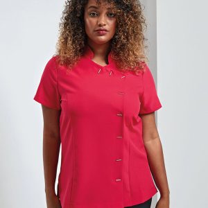 A woman is standing in the image, dressed in a red tunic. The background is white, and the image is taken from a close perspective, revealing the woman's facial features.